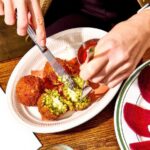 Diner slicing open arancini with a fork