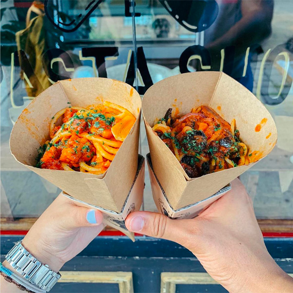 Women holding out a spaghetti cone in each hand